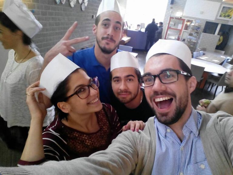 Teilnehmende mit Kochmützen machen ein Selfie bei einem Kochworkshop