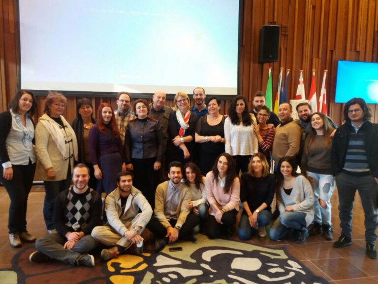 Group photo of participants in a conference hall with European flags