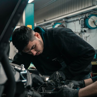 Autószerelő egy autó motorján dolgozik